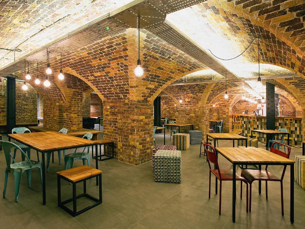Zona de refeições do Wombat’s City Hostel London com teto de pedra e algumas mesas e cadeiras.
