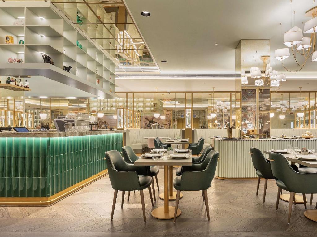 Área de refeições e bar do The Emerald House Lisbon com lustres, mesas com cadeiras estofadas e elementos decorativos
