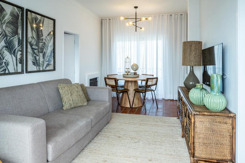 Sala de estar e jantar integrada com sofá cinzento e mesa de madeira na Villa Eira (Vila Nova de Milfontes)
