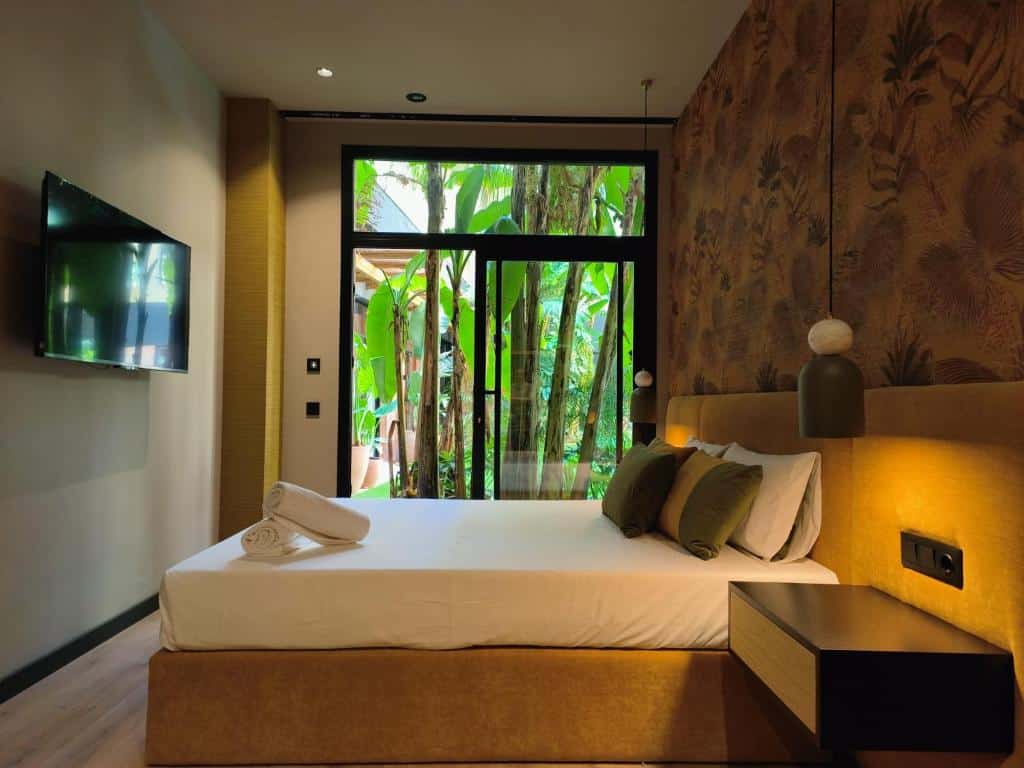 Quarto do Saman Hotel Boutique com vista para vegetação tropical, com cama king size, TV de ecrã plano na parede e apontamentos em madeira escura.