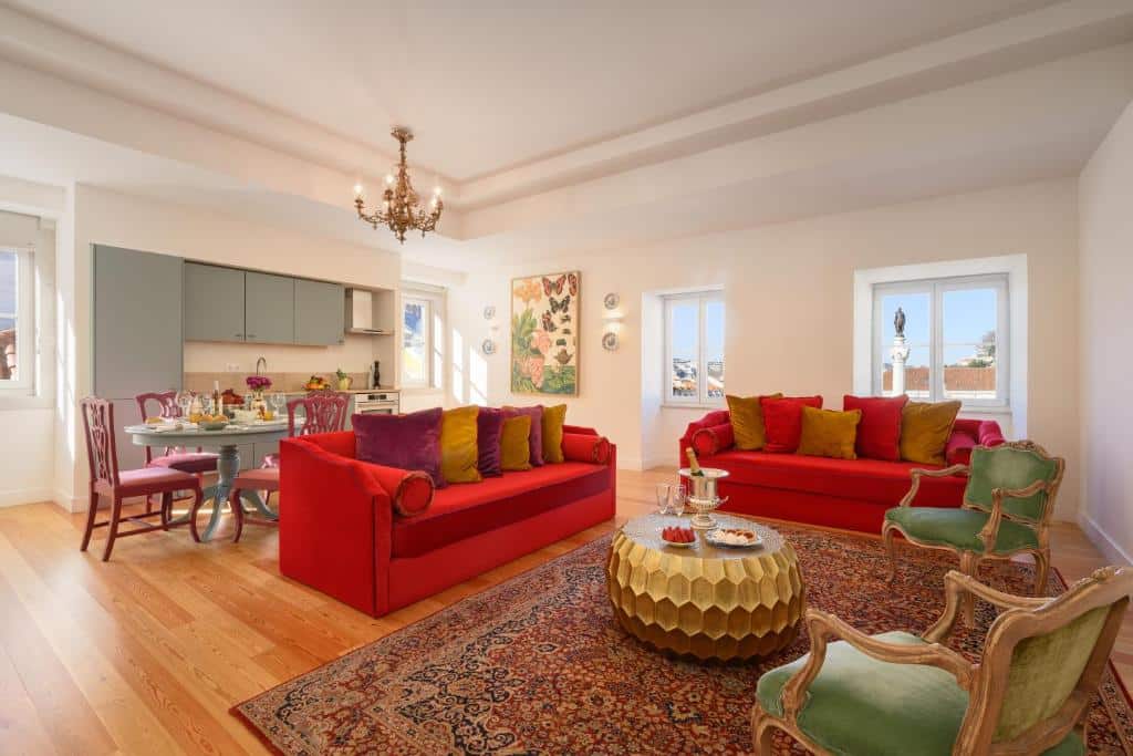 Sala de estar espaçosa integrada com cozinha no Residentas Arco do Bandeira, com quatro janelas, dois sofás grandes, duas poltronas e uma mesa de centro; do lado esquerdo há uma pequena cozinha com mesa de jantar de quatro lugares