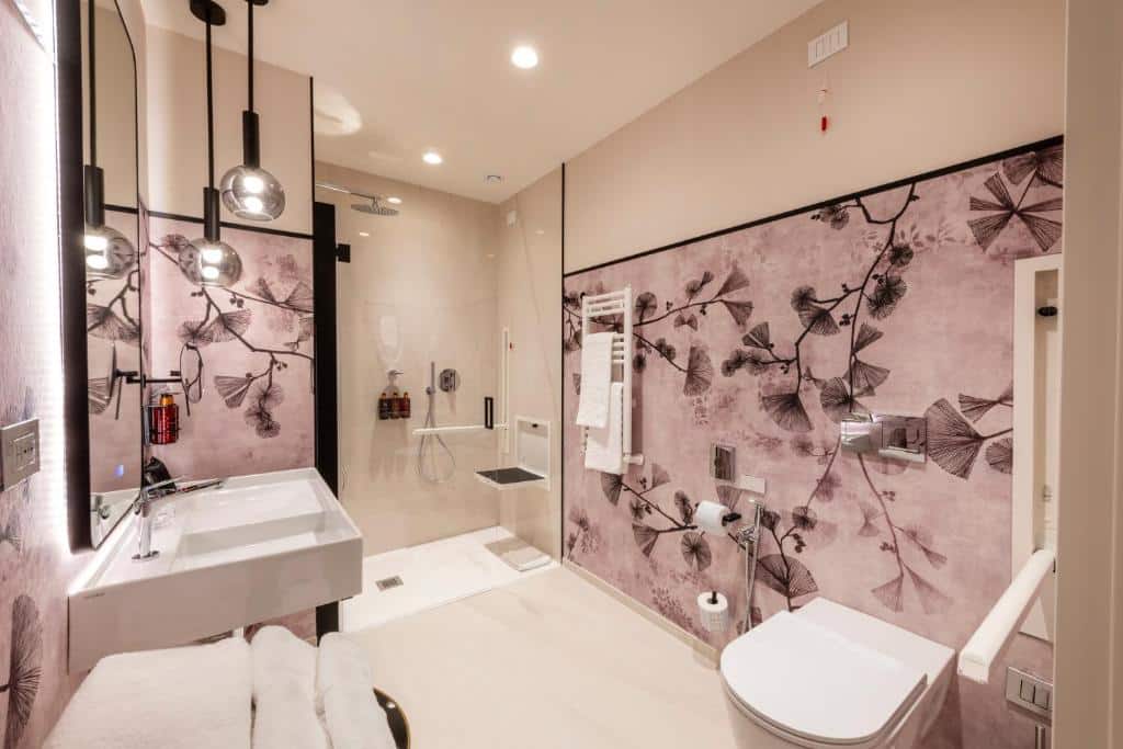 casa de banho do H10 Palazzo Galla, um dos melhores hotéis em Roma, com acessibilidade para pessoas com deficiência: barras de apoio, cadeira de banho embutida, sanita mais alta e lavatórios mais baixos, num ambiente amplo e decorado