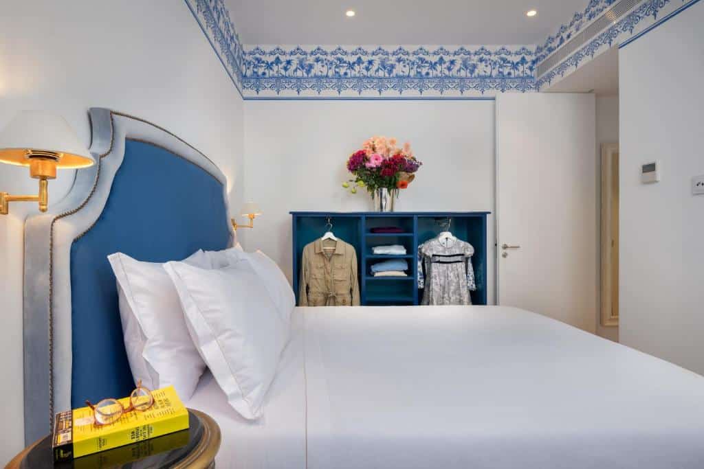 Quarto do Residentas Aurea decorado em azul e branco, com uma cama de casal e um pequeno roupeiro de conceito aberto com cabide e prateleiras