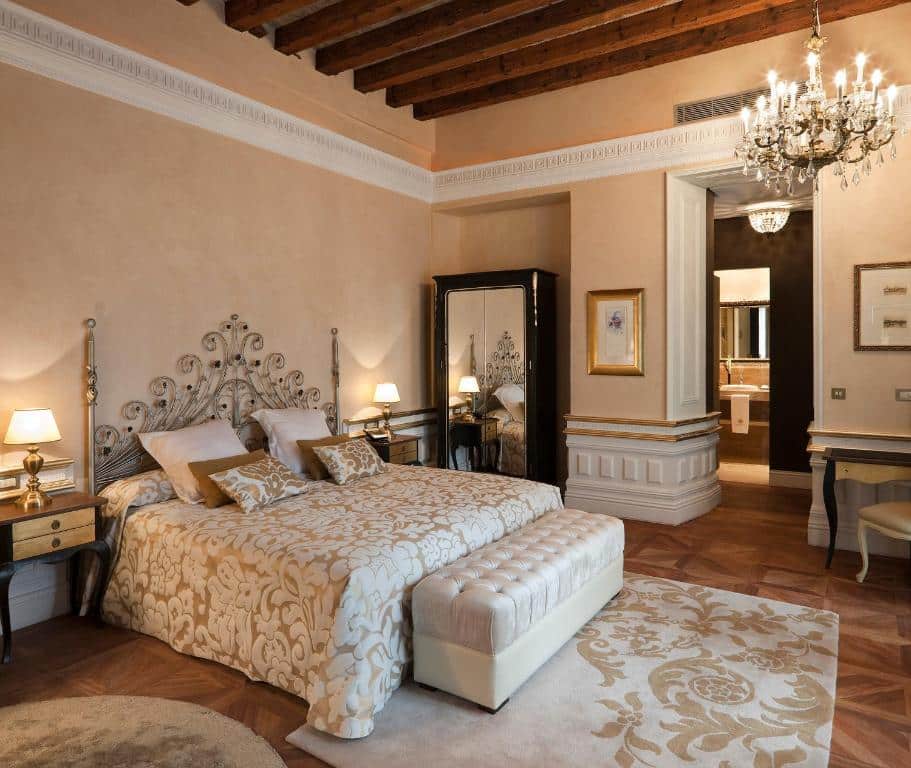Quarto espaçoso do Hotel Casa 1800 Sevilla, com cama de casal, banco aos pés e uma cómoda de cada lado.