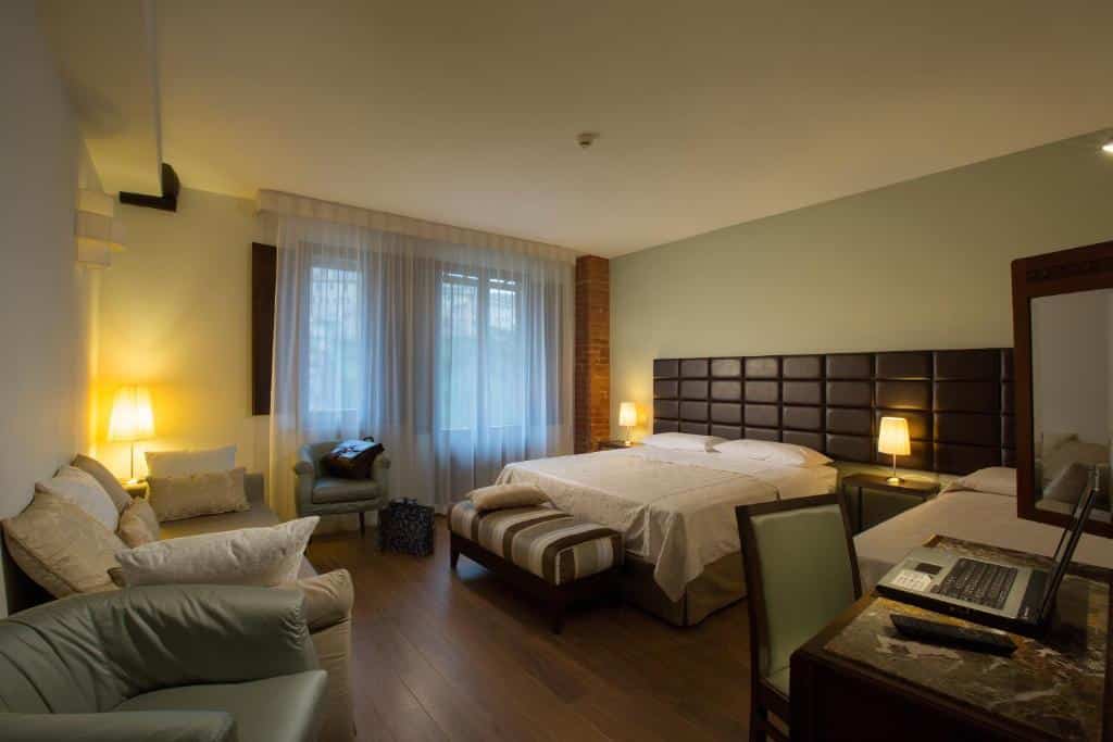 Quarto de hotel confortável com cama de casal, poltrona e mesa com portátil