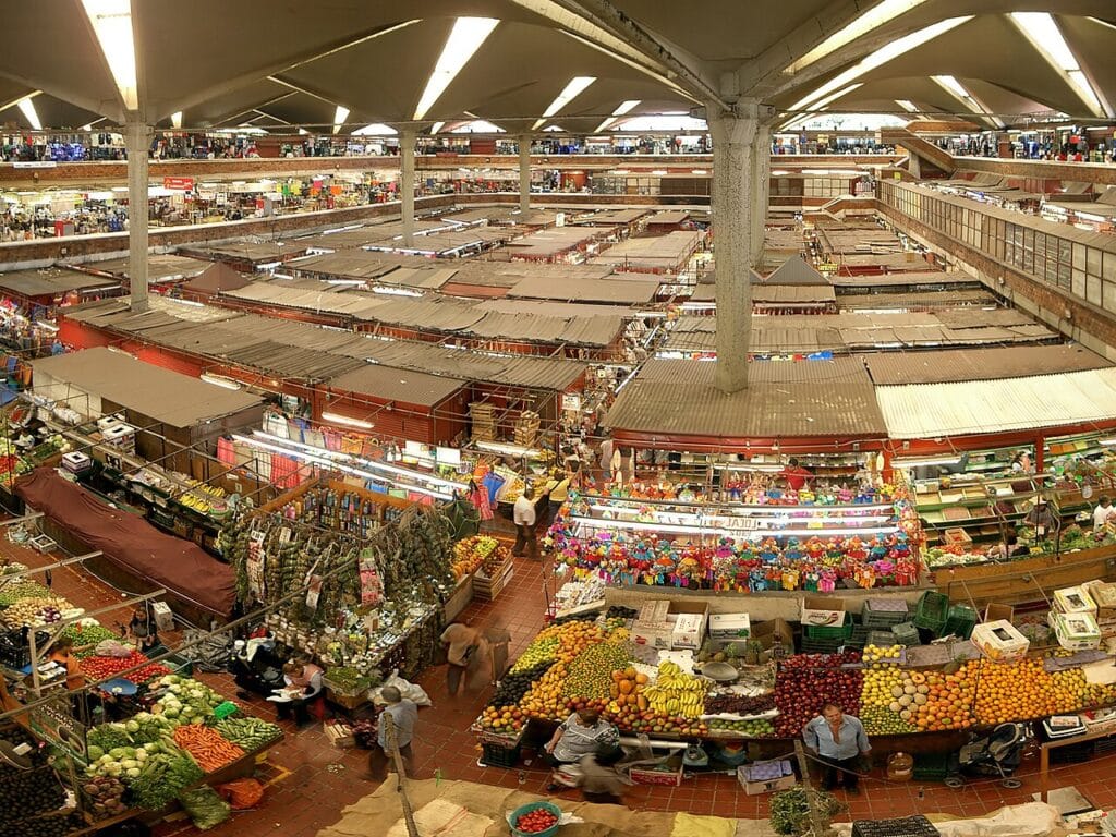 Mercado Libertad com grandes espaços de venda de fruta e legumes, com uma variedade colorida de produtos expostos nas bancadas.