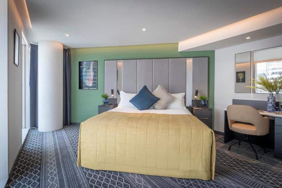 Quarto do Marlin Hotel Stephens Green com paredes verde-menta, cama king size com cabeceira de veludo cinzento, candeeiros pretos, quadros de arte moderna e janelas amplas.