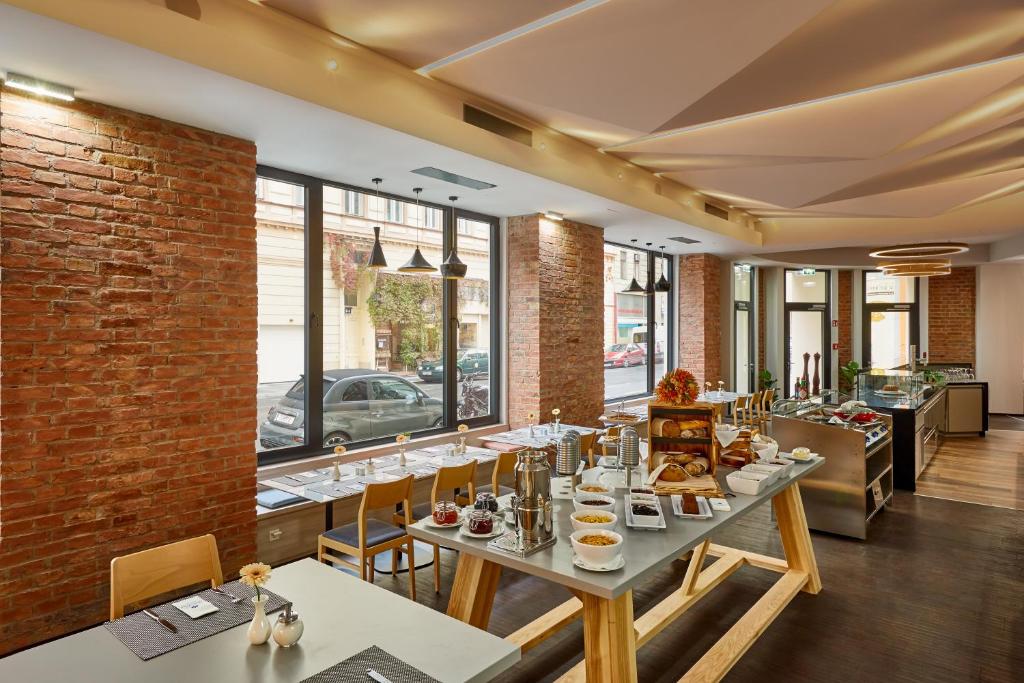 Buffet de pequeno-almoço no H+ Hotel Wien, servido numa zona de refeições moderna, com paredes de tijolo, janelas grandes e mesas ao longo da janela.