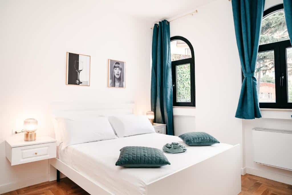 Quarto do Vista Napoli Residence by Casa Napoletana com cama de casal, cortinas e almofadas verdes, decorado com quadros minimalistas a preto e branco.