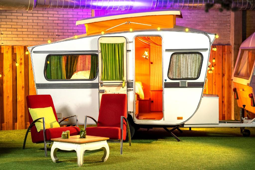 Caravana vintage do Outside Inn com cadeiras à frente, relva artificial e bastante iluminação
