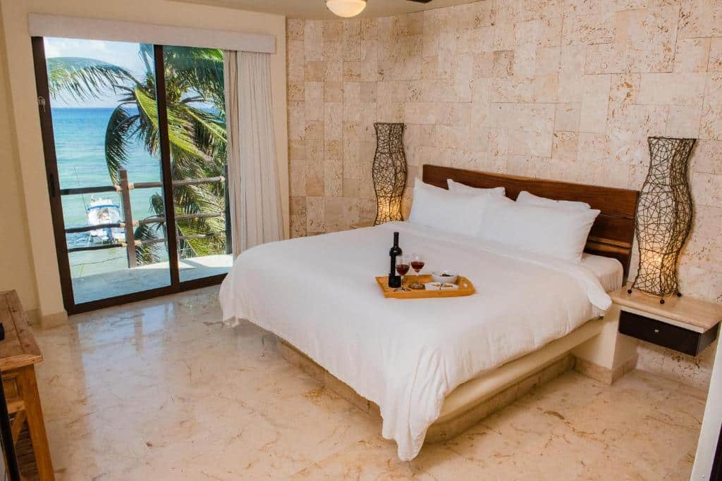 Quarto do El Taj Oceanfront and Beachside Condo Hotel com vista para a praia, cama de casal com roupa branca e bandeja com vinho e petiscos.