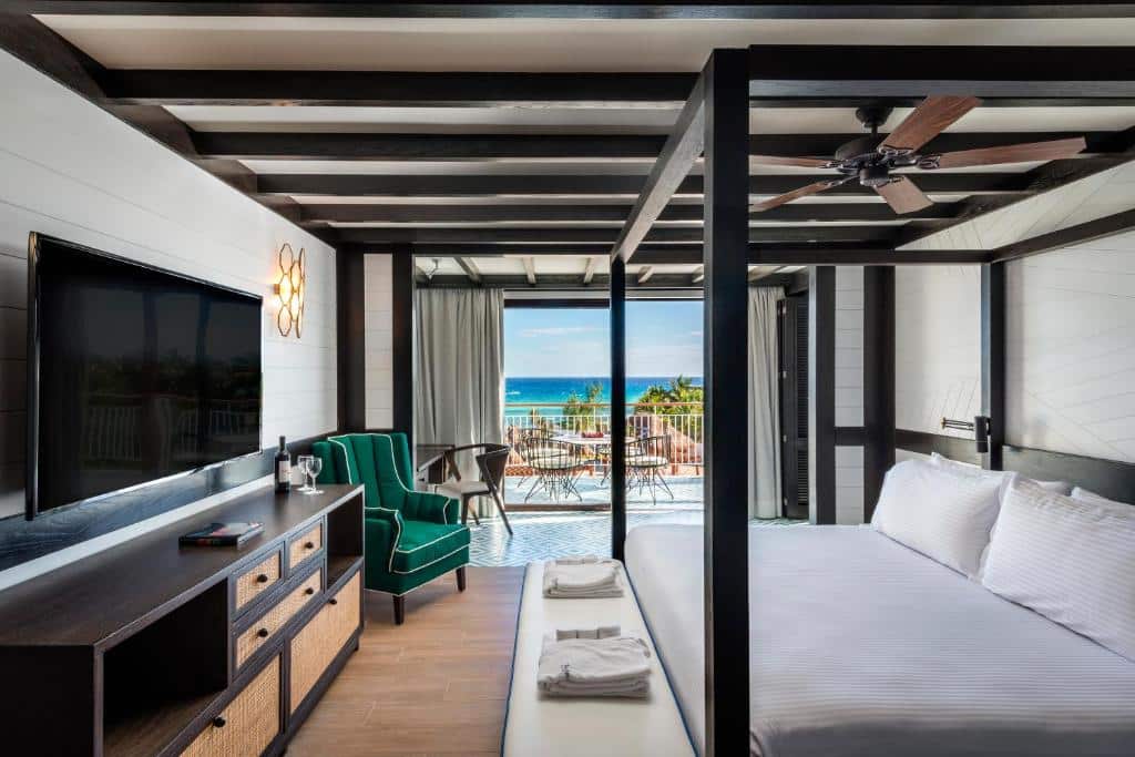 Quarto do Ocean Riviera Paradise com tudo incluído, com vista para a praia pela varanda e cama king size ao centro, de frente para uma TV na parede.