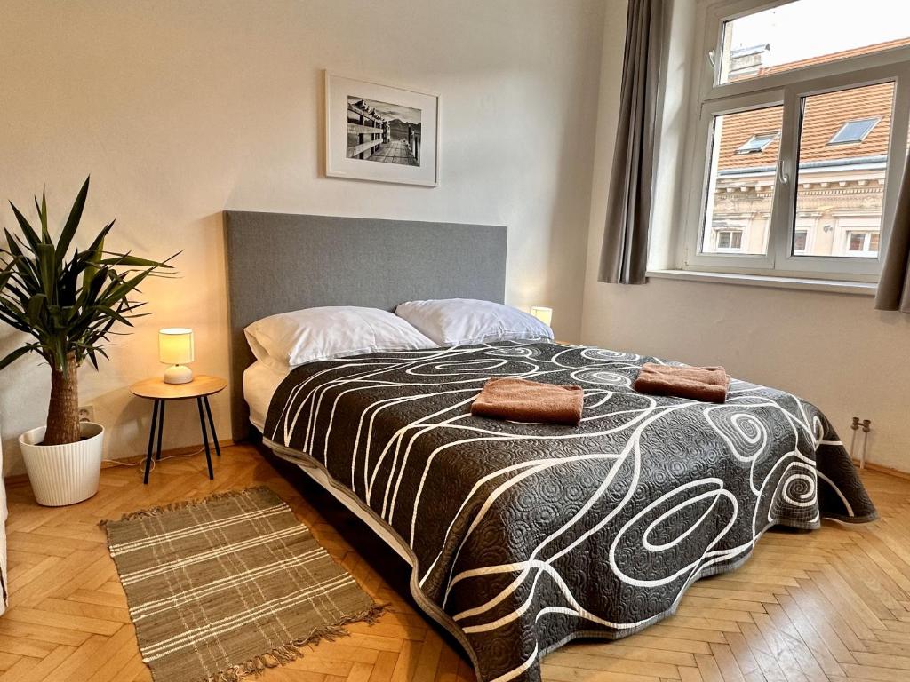 Cama de casal bem feita da Pension Sklep, com uma colcha estampada, duas toalhas e mesas de cabeceira num quarto bem iluminado e arrumado.