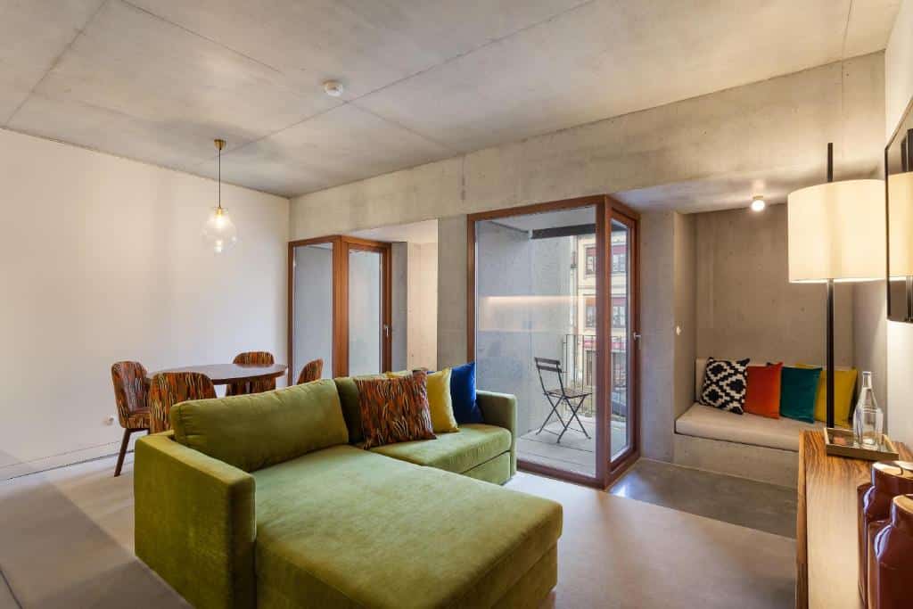 Sala de estar do S.Bento Residences, com sofá à esquerda, uma cómoda de madeira em frente e uma mesa com quatro cadeiras.