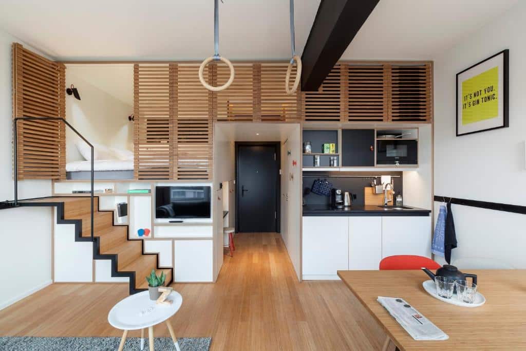 Apartamento-estúdio moderno do Zoku Amsterdam, que ilustra onde ficar em Amesterdão: cama em mezanino, kitchenette compacta, mesa de refeições, argolas de ginástica e decoração minimalista.