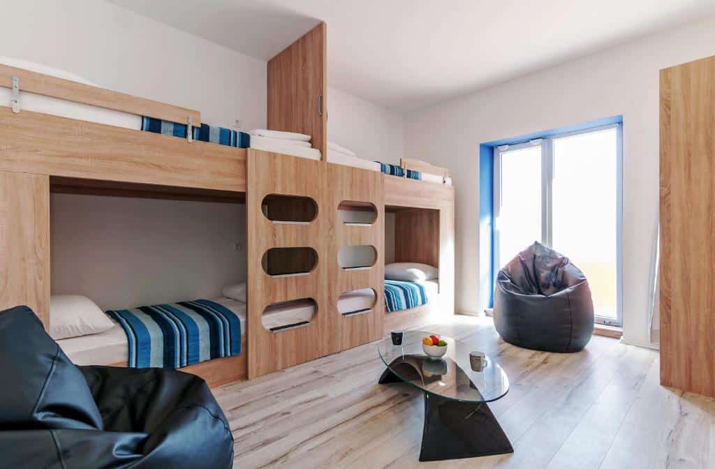 Quarto de hostel com beliches de madeira, pufes e mesa de centro de vidro, no Sky Hostel, em Zadar