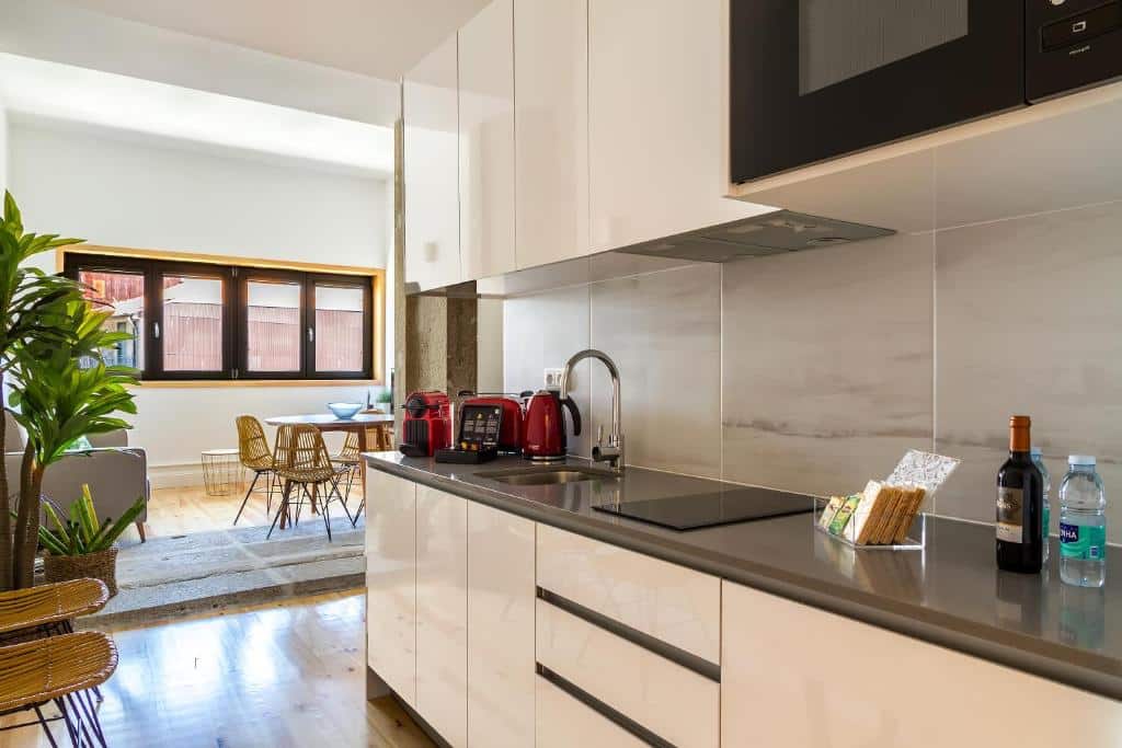 Cozinha do InSitu Formosa 178, com armários à direita, micro-ondas e lava-loiça e, ao fundo, uma mesa redonda com cadeiras.