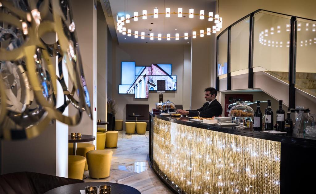 Receção com lustre redondo, poltronas amarelas e mesas de apoio no The Square Milano Duomo