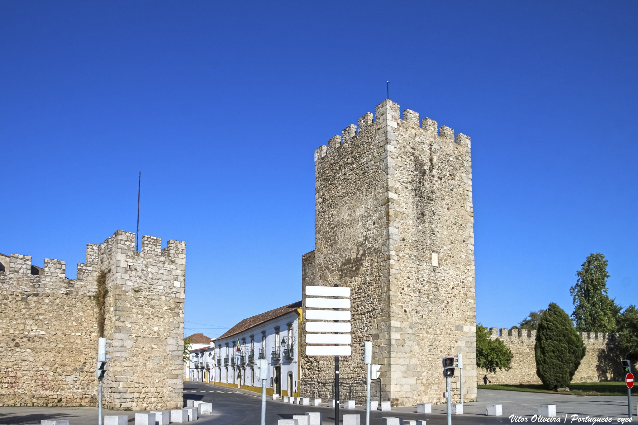 Muralhas de Évora com caminho de pedras e relva verde sob céu azul