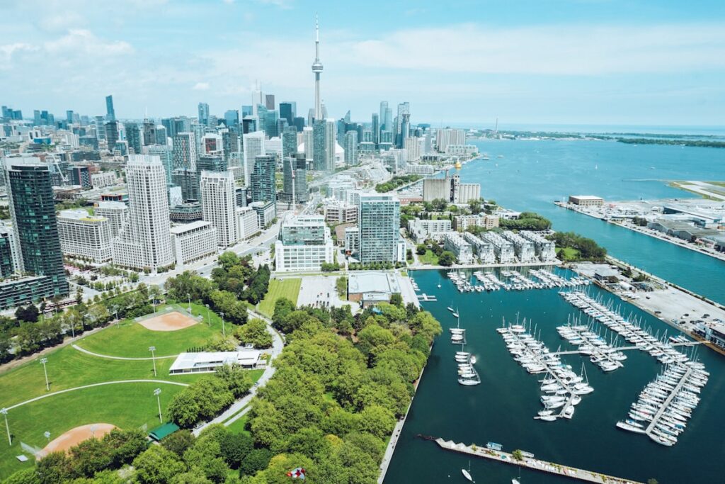 Skyline de Toronto no Canadá com arranha-céus modernos e edifícios comerciais, marina com barcos e iate, e área verde de parque em redor