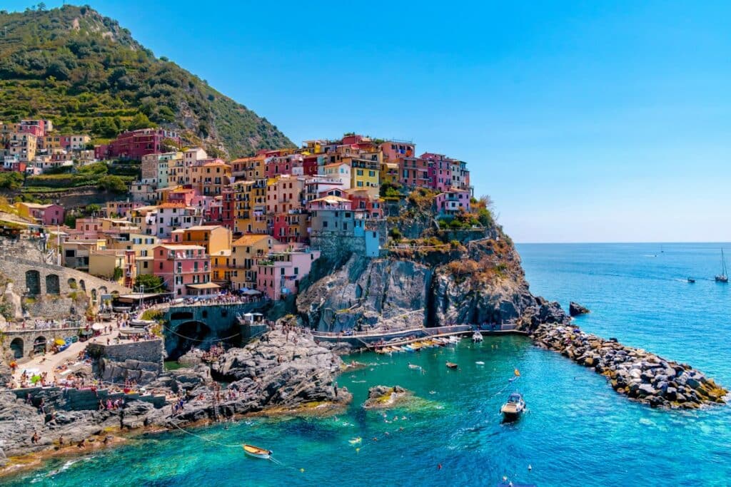 Vila costeira de Manarola, com casas coloridas na encosta rochosa junto ao mar turquesa