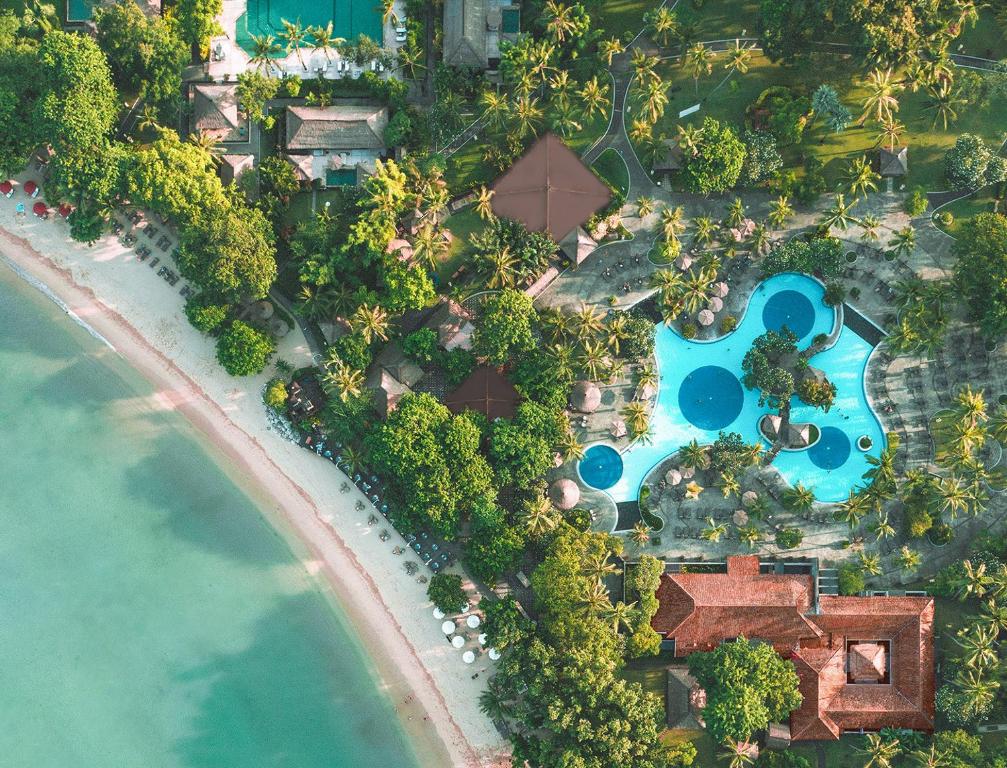 Vista aérea de um resort à beira-mar com piscinas e vegetação, junto a praia de areia branca, no Melia Bali, em Nusa Dua.