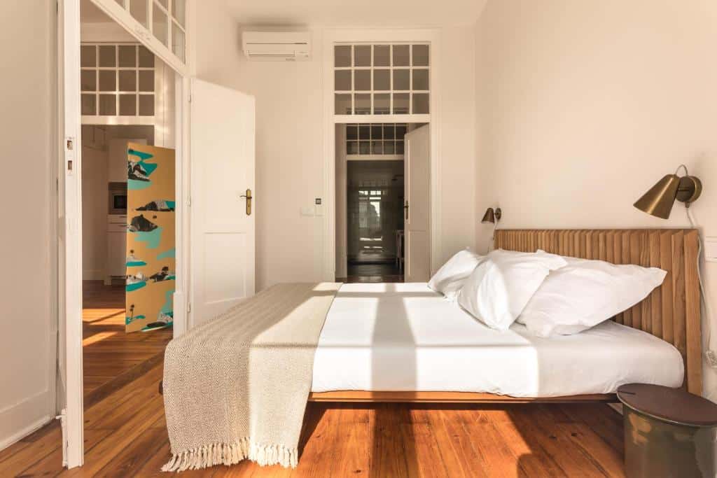 Quarto do The Visionaire Apartments com uma cama de casal espaçosa, uma janela ampla, ar condicionado de teto e candeeiros nas laterais da cama