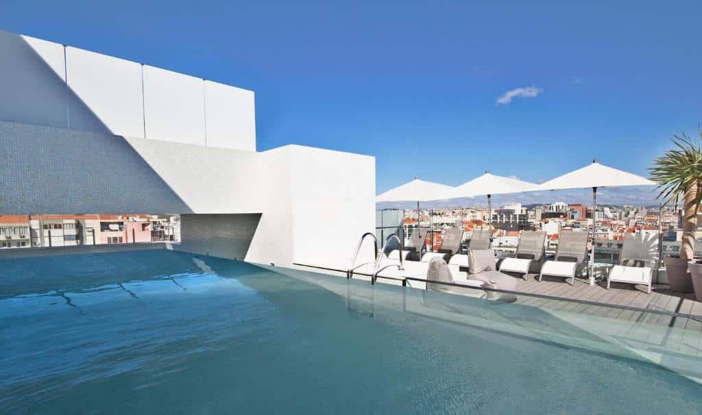 Piscina na cobertura do Hotel White Lisboa, com espreguiçadeiras brancas e chapéus de sol no deck em redor