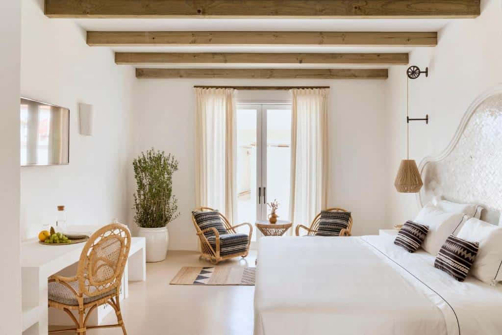 Quarto do Quinta da Comporta – Wellness Boutique Resort, com cama de casal, secretária e dois cadeirões.