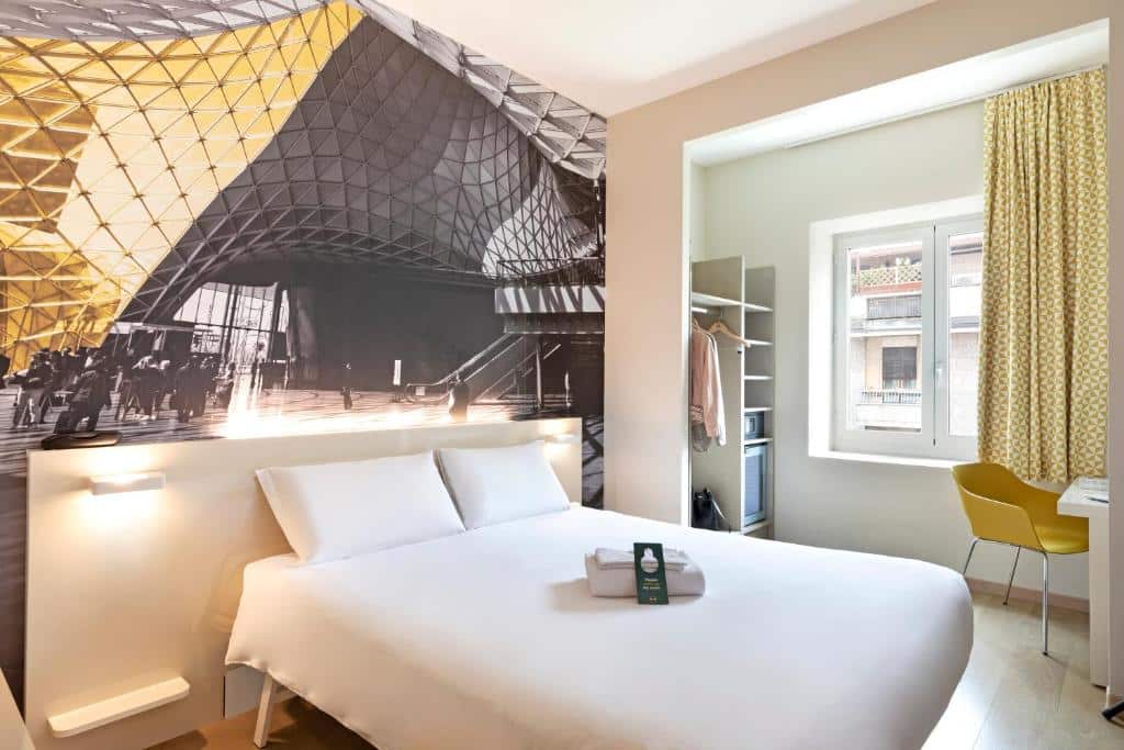 Quarto com cama de casal, papel de parede em tons de amarelo e cinzento, secretária e roupeiro brancos