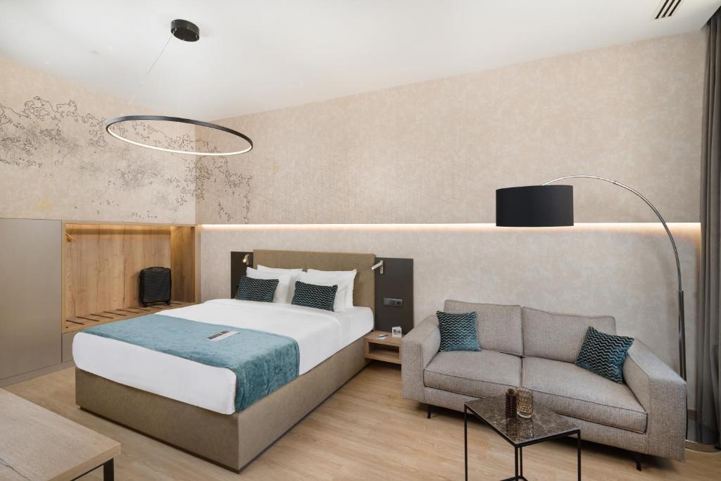 Quarto do Hotel Vision Budapest com uma cama de casal, apontamentos em azul-petróleo, um sofá cinzento, mesa lateral e decoração minimalista.