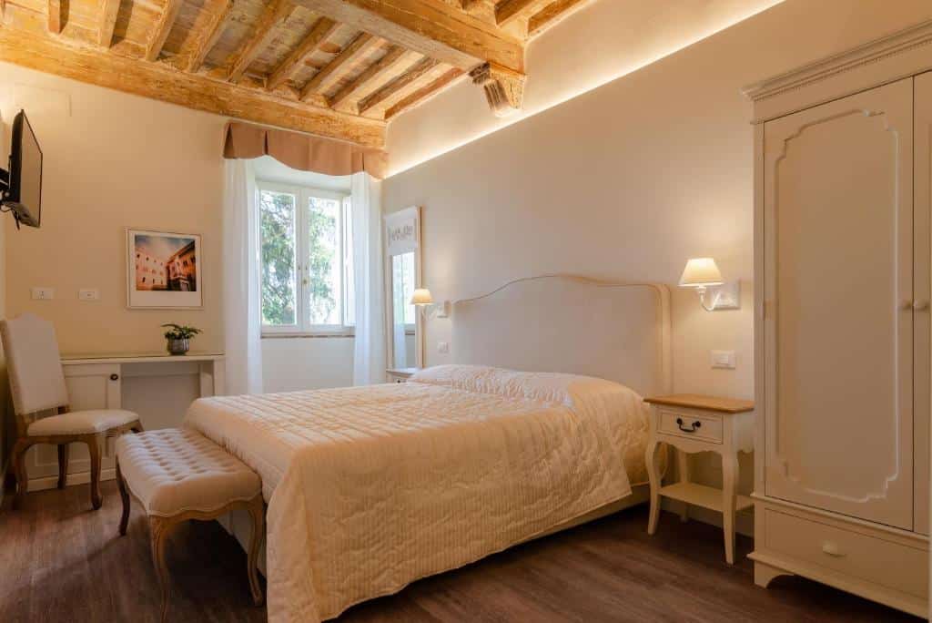 Quarto de hotel clássico com cama de casal, secretária e roupeiro creme