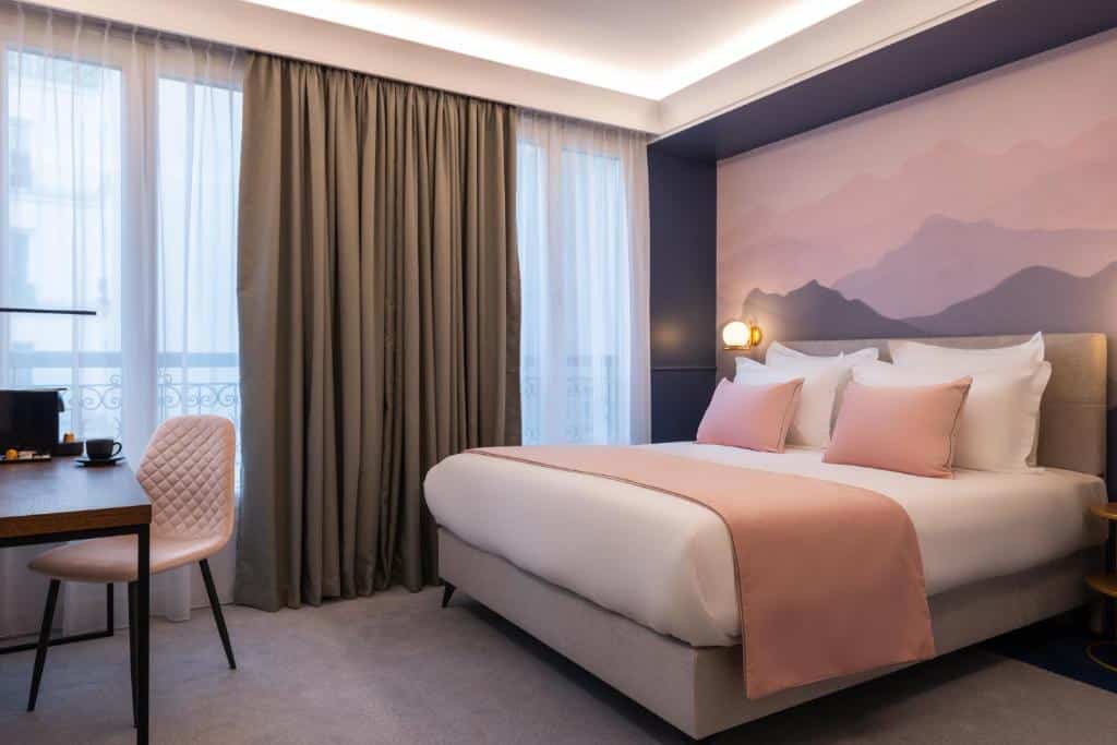 Quarto do Hôtel Le Milie Rose com cama de casal, roupa de cama cor-de-rosa e branca, secretária e mural de montanha na parede.