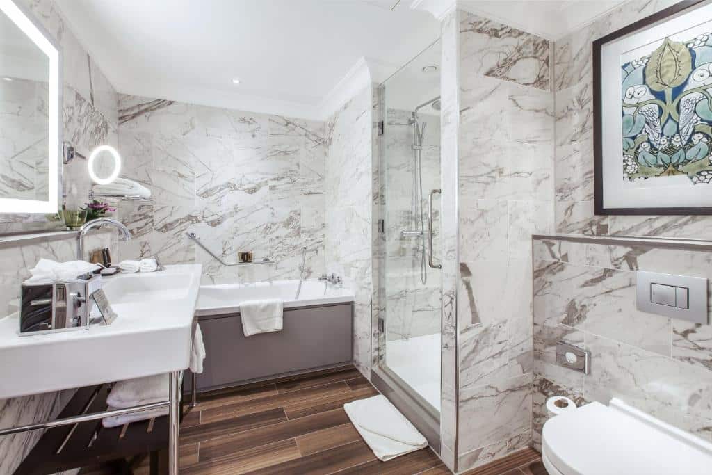 Casa de banho do St. James’ Court, A Taj Hotel, London em mármore, com box em vidro, banheira de hidromassagem, lavatório largo e espelho