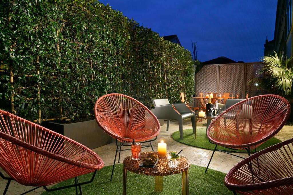 Lounge partilhado do Milan Suite Hotel com vasos de plantas, cadeiras, mesinhas e iluminação indireta