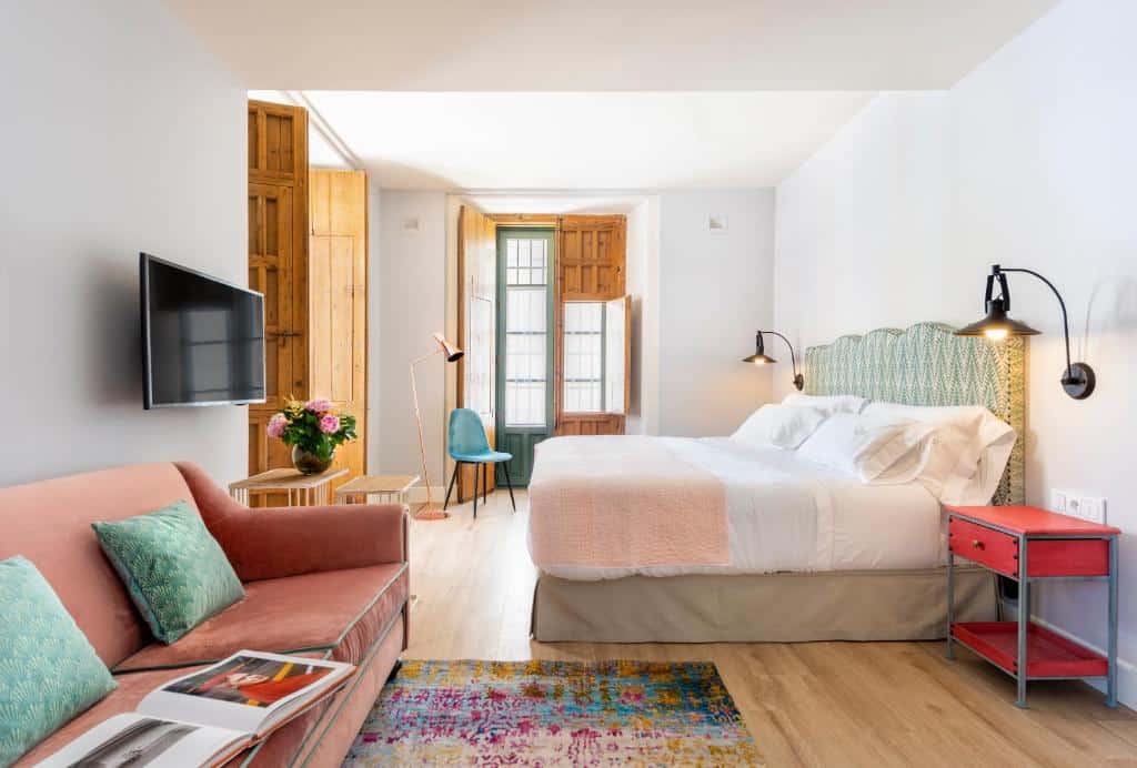 Quarto no Palacio Bucarelli com sofá, cama de casal virada para a televisão e muita luz natural.
