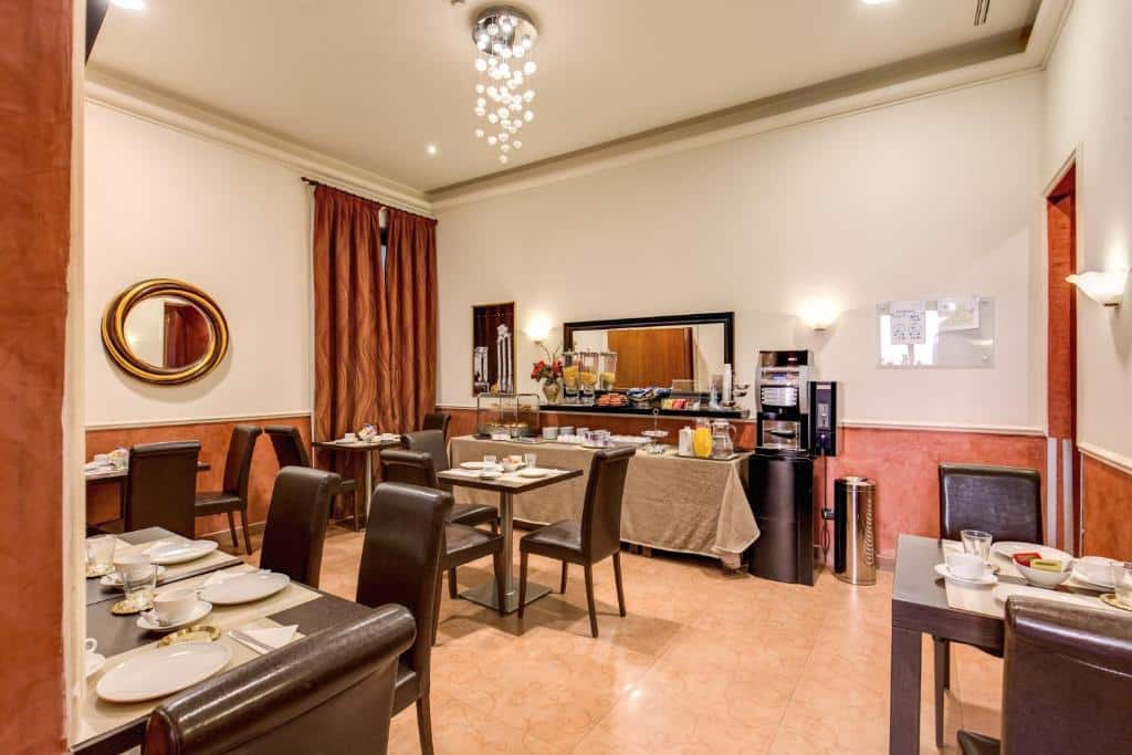 salão do Hotel Everest Inn Rome com mesas e cadeiras de madeira, uma bancada com alimentos e um lustre por cima