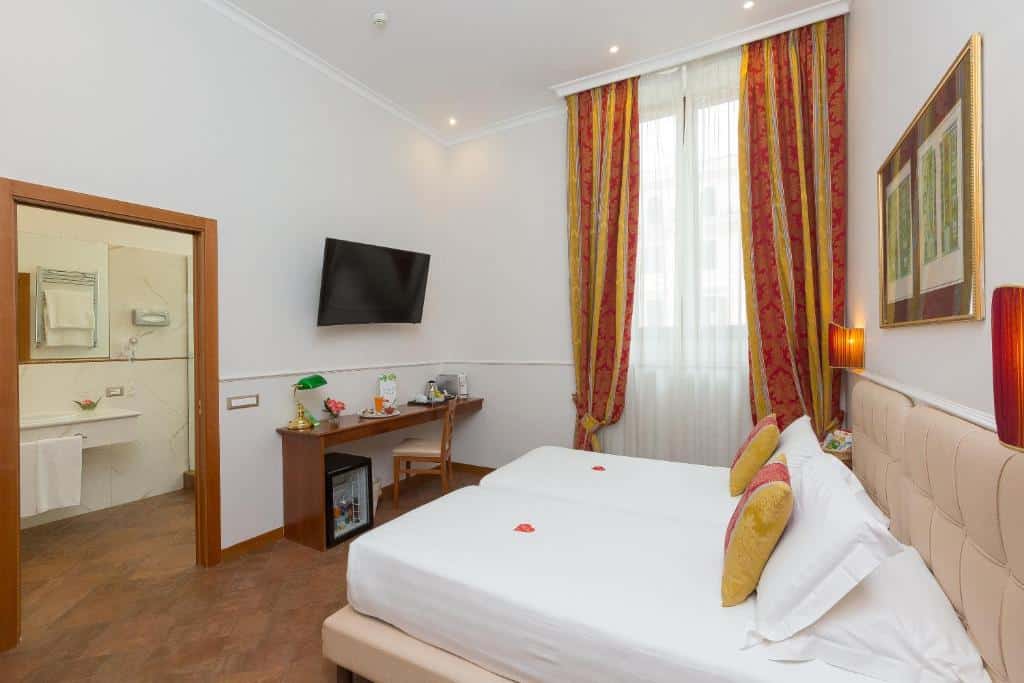 quarto do Hotel Milton Roma, um dos hotéis baratos em Roma, com camas juntas a formar uma maior, janela grande com cortinados coloridos em tons de amarelo e laranja, televisão e cómoda em frente e entrada para a casa de banho ampla revestida a pedra