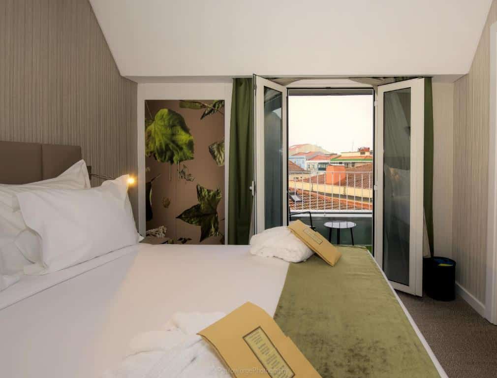 Quarto do The Leaf Boutique Hotel Lisbon com uma cama de casal e uma pequena varanda com mesa e cadeira.