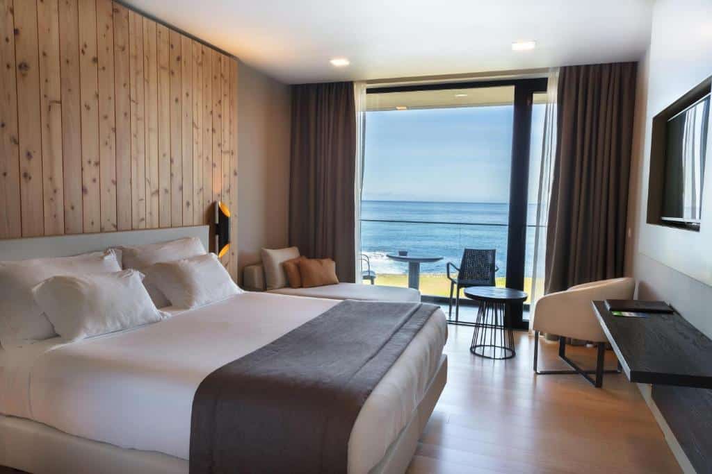 Quarto do Pedras do Mar Resort & Spa, com cama de casal, televisão e sofá.