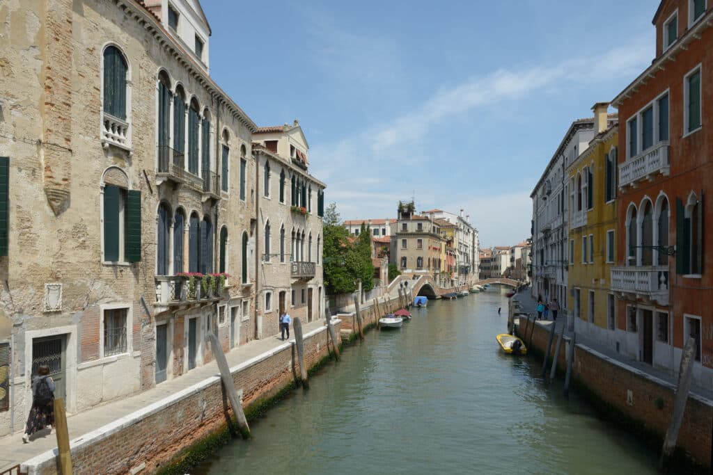 Paisagem magnífica dos canais de Veneza, com belos edifícios históricos e pontes de pedra refletidos na água verde-azulada