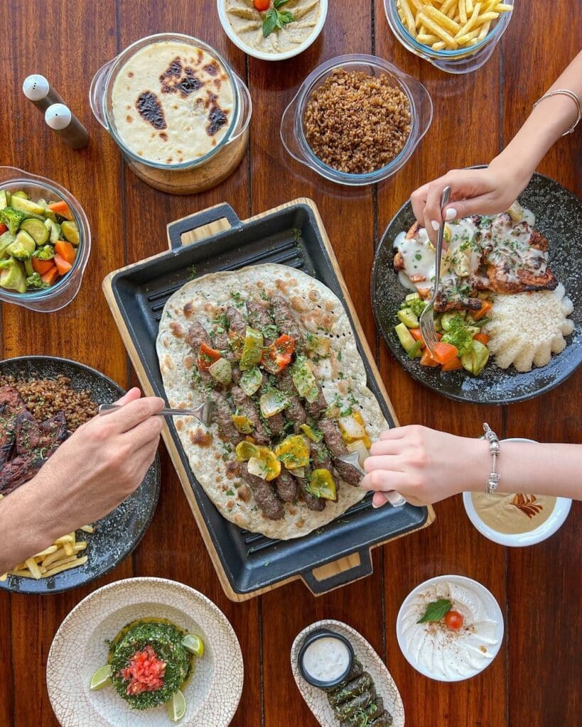 Prato de kofta partilhado num restaurante no Cairo, com pão árabe, carnes e legumes em pratos mais pequenos