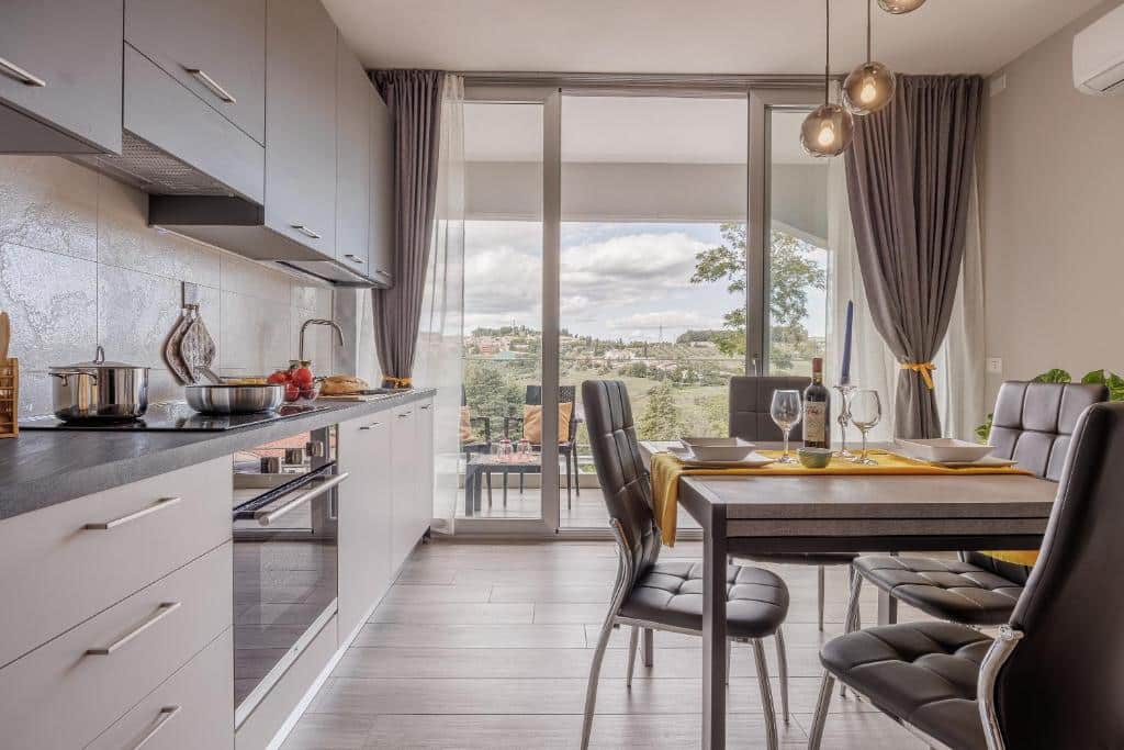 Cozinha equipada moderna com mesa de jantar e vista para zona verde arborizada