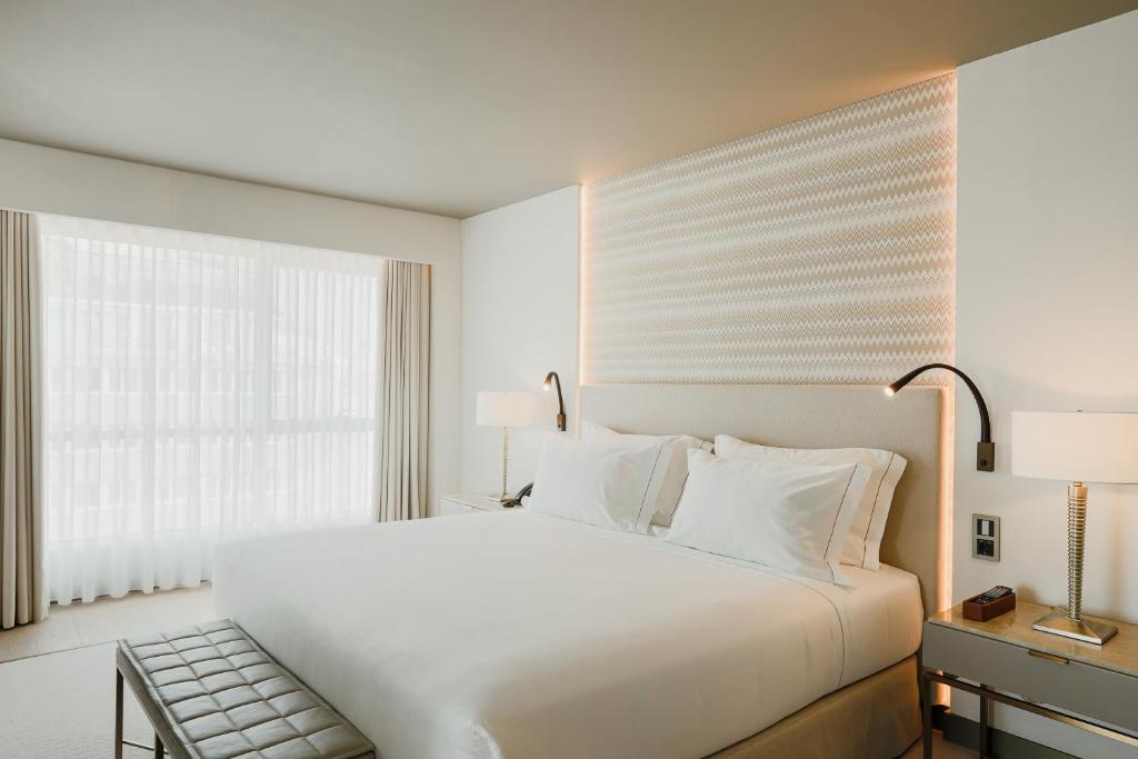 Quarto do EPIC SANA Marquês Hotel, com cama de casal e mesas de cabeceira com candeeiros.