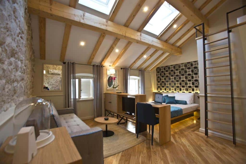 Quarto de hotel acolhedor com decoração rústica, cama de casal e zona de trabalho com portátil, no Borelli Palace & Borelli Blue (Cidade Velha)