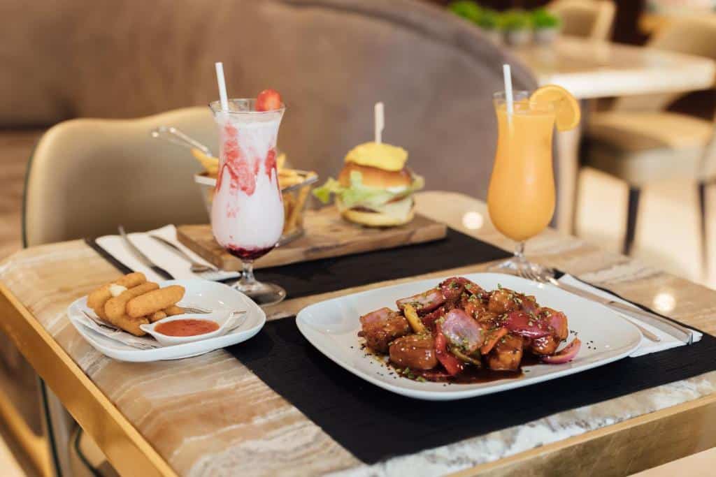 Refeição servida no Hotel MeraPrime Gold Lisboa com batido, mini-hambúrguer e batatas fritas, um sumo natural e um prato com carne, cebola e molho