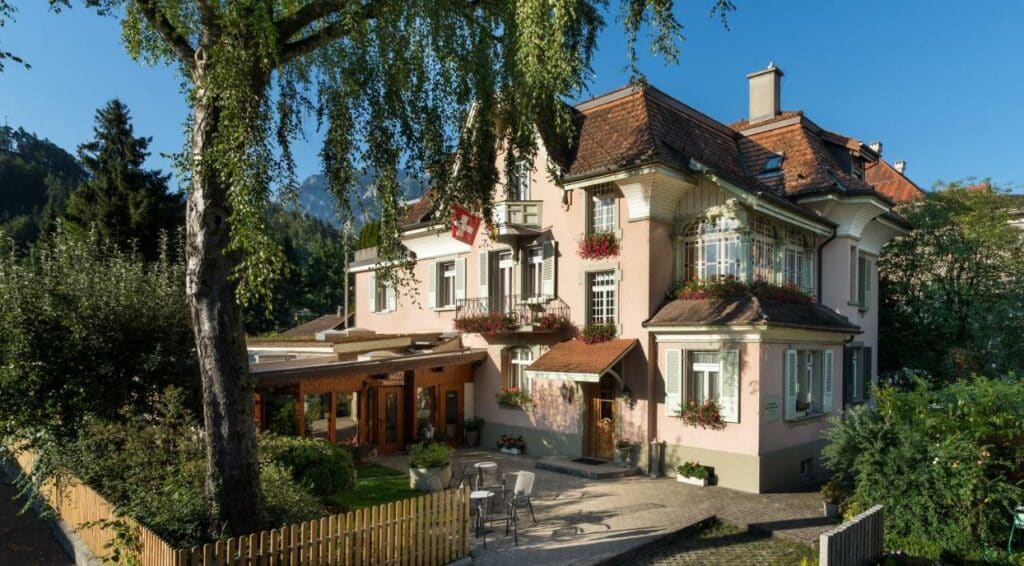 Fachada do Swiss Inn & Apartments durante o dia, com jardim em redor.